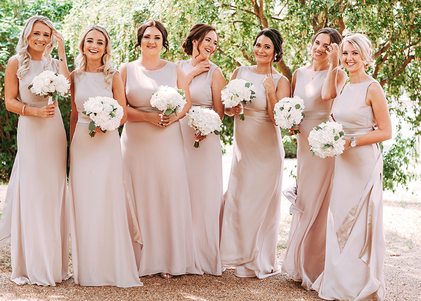 Bridesmaids in blush gowns holding white bouquets
