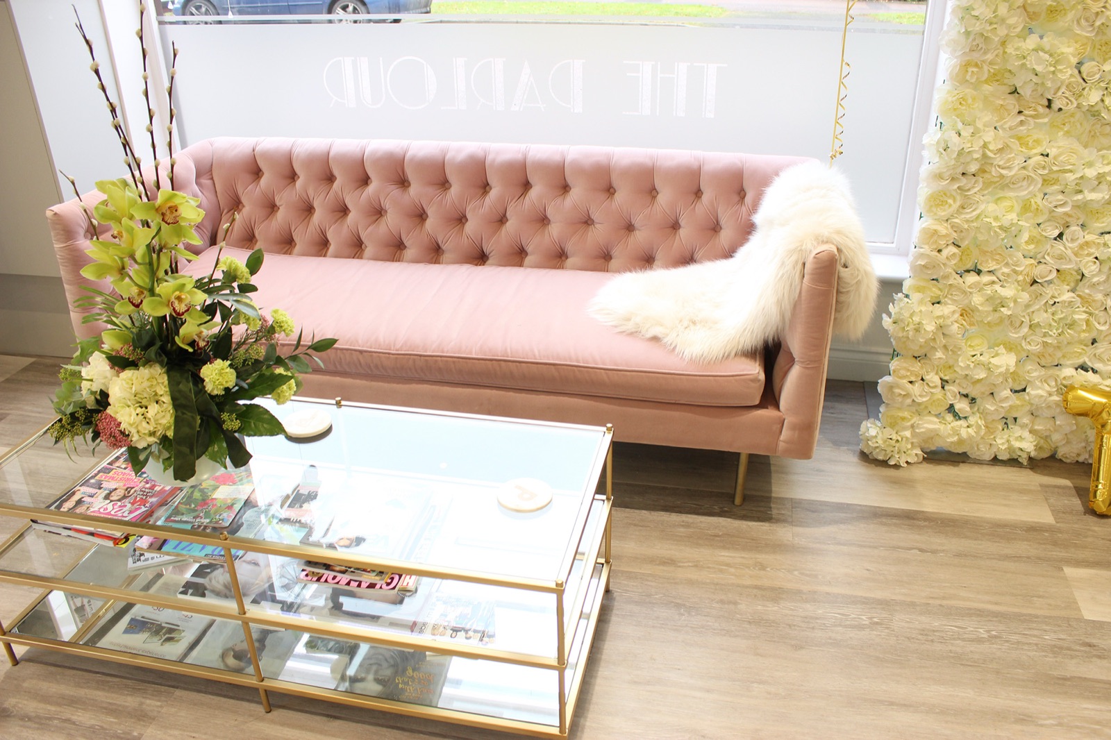 A pink velvet sofa and gold coffee table in the waiting area